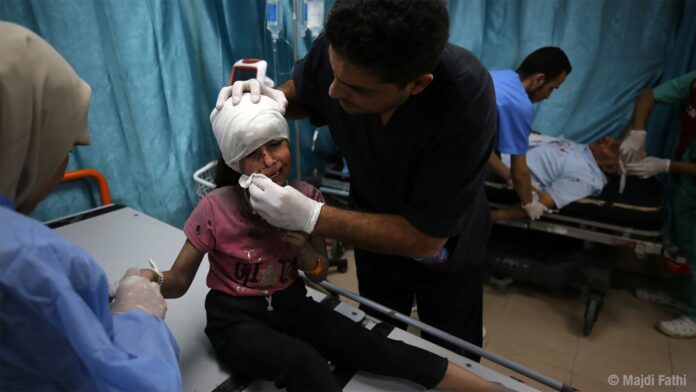 Médico atendendo neno ferido en Gaza. Foto de Majdi Fathi