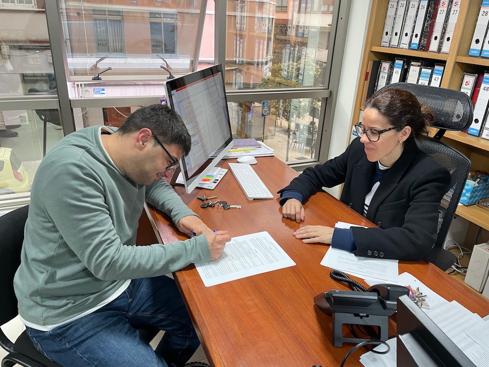 Un usuario de Down Coruna asinando o seu contrato de aluguer